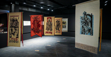 Vista da exposição Arte Gravada, com estandartes suspensos em uma sala escura